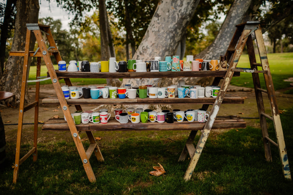 Display of coffee mugs on old ladders and wood planks at a wedding rececption