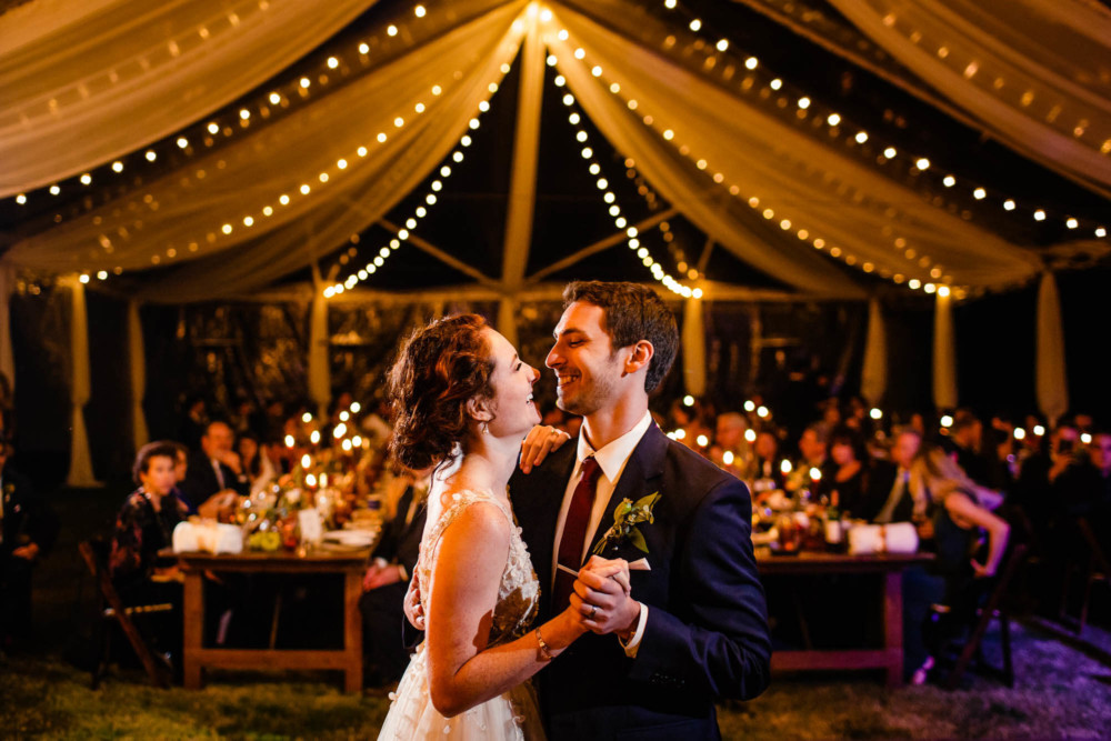 Bride and grooms first dance under a clear tent and market lights