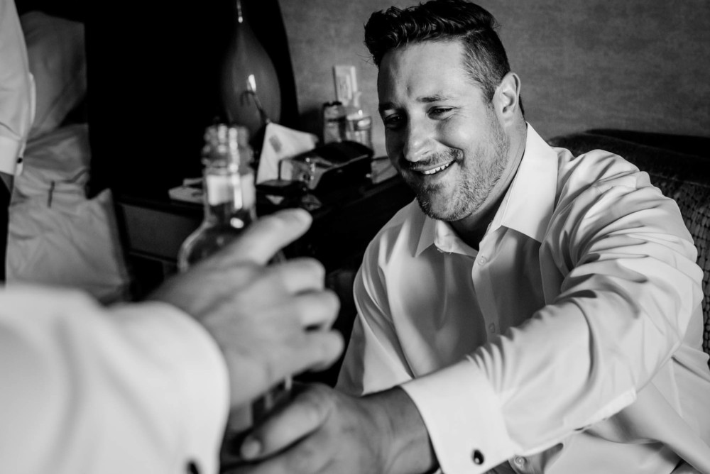 Groom passing the bottle of whiskey to a friend