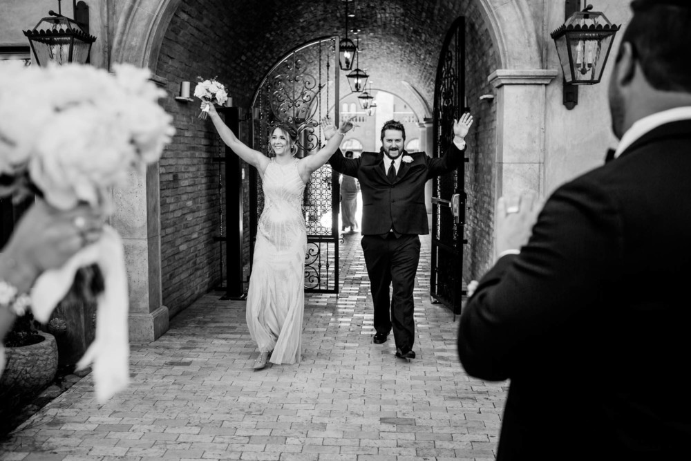 Maid of honor and best man throw their arms up in victory as they approach the bride and groom after the ceremony