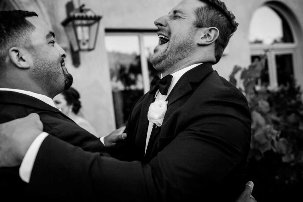 Groom lets out a huge laugh with his groomsman