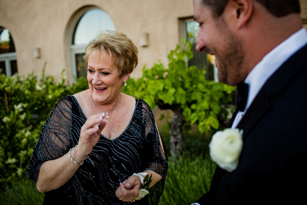Mother of the groom laughs in reaction to her son