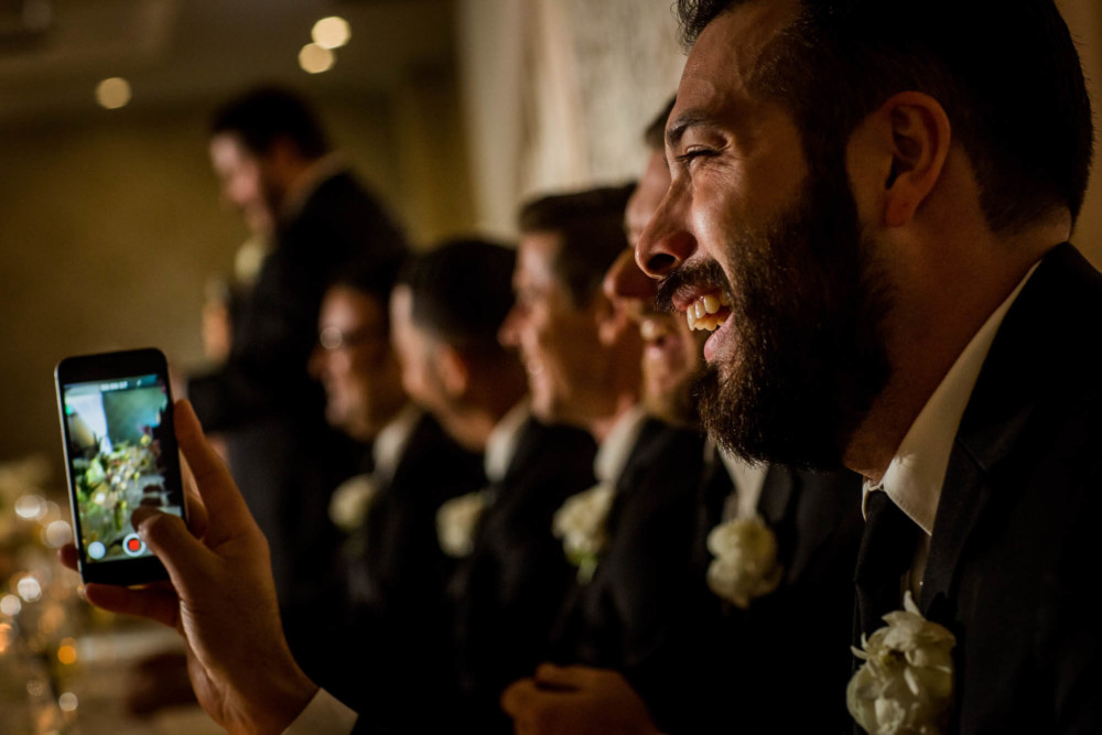 Groomsman records the speeches with his phone