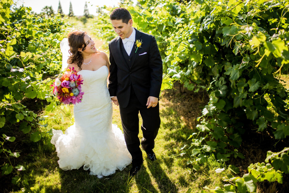 Bride and groom walking through vineyard