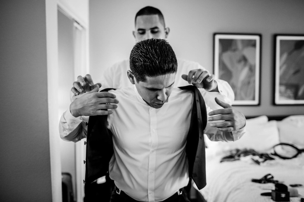Groomsman helping the groom with his vest