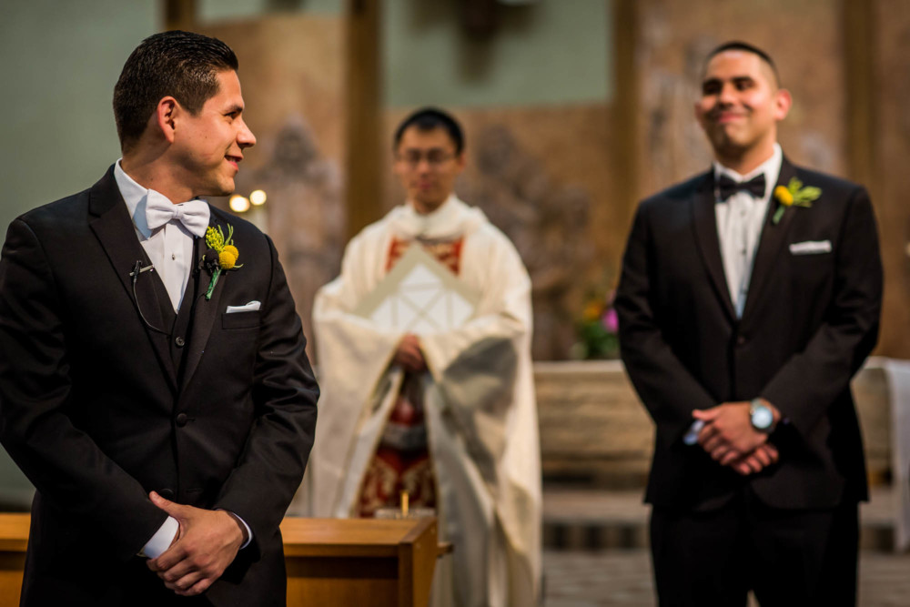 Groom shares a laugh with his best man at the altar waiting for the bride to come down the aisle
