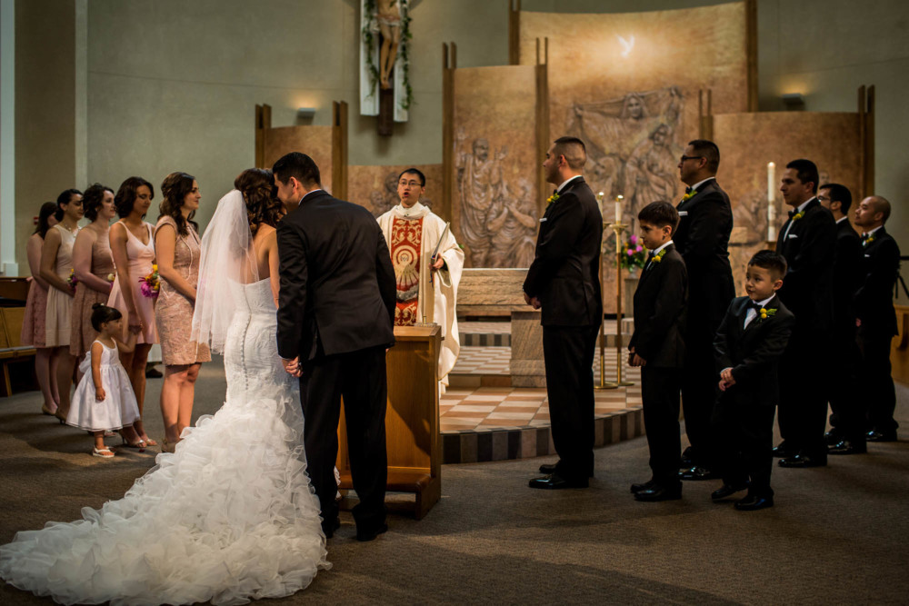 Groom whispers in his bride's ear during their wedding ceremony at Holy Spirit Catholic Church