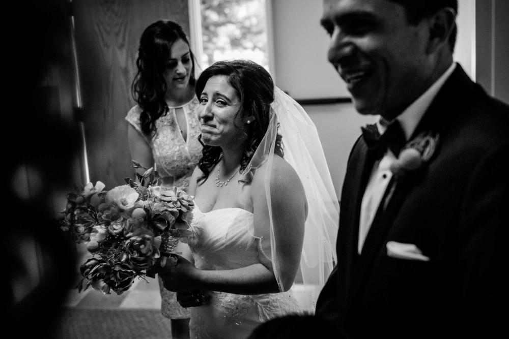 Bride holds back happy tears looking at the groom