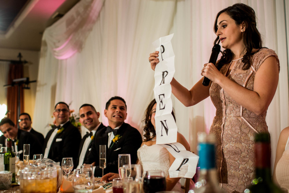 Maid of Honor giving wedding toast holding long sign saying prenup