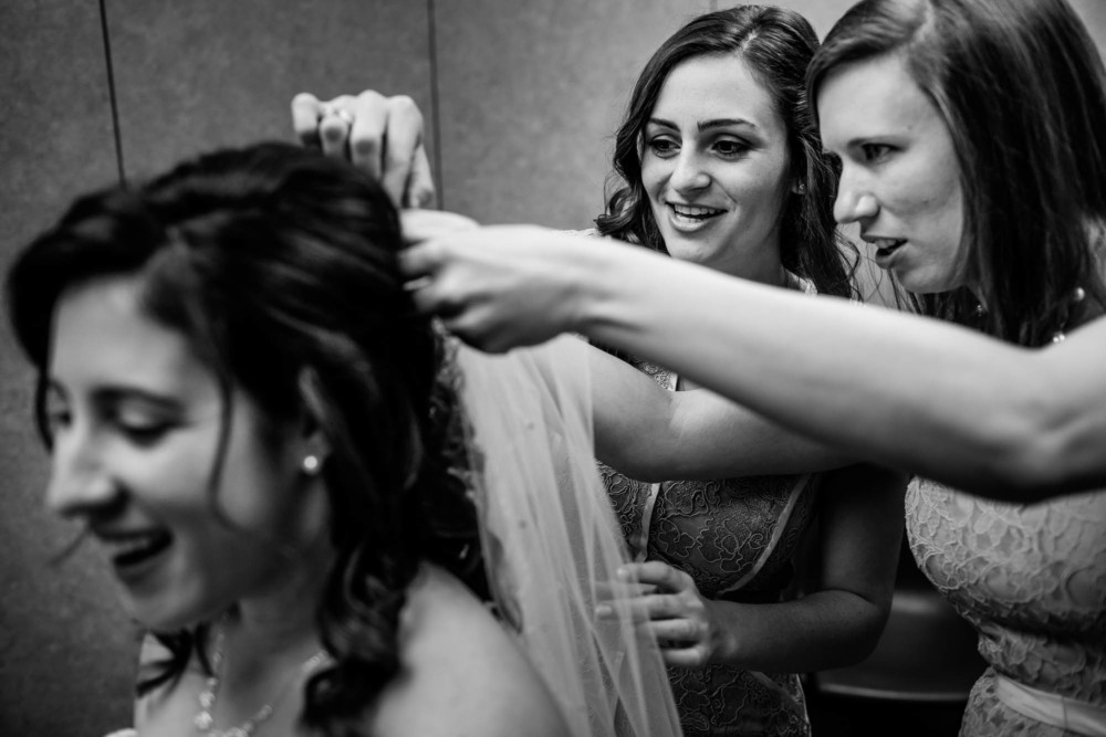 Bridesmaids concentrating on putting on the bride's veil