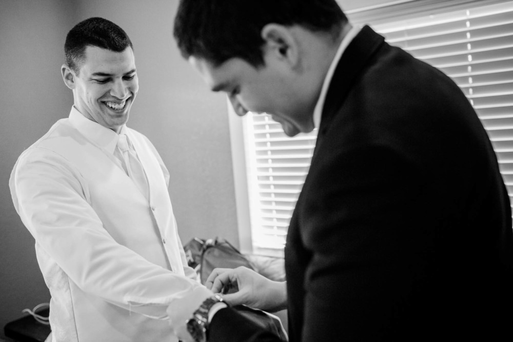 Groomsman helps groom with cufflinks