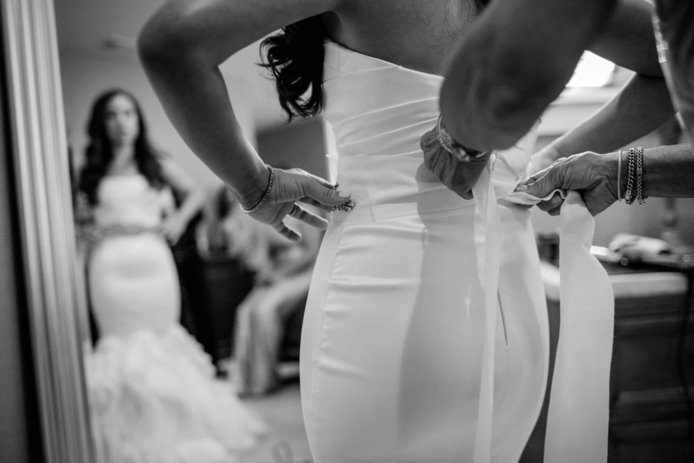 hands tie a bow on the back of a wedding dress