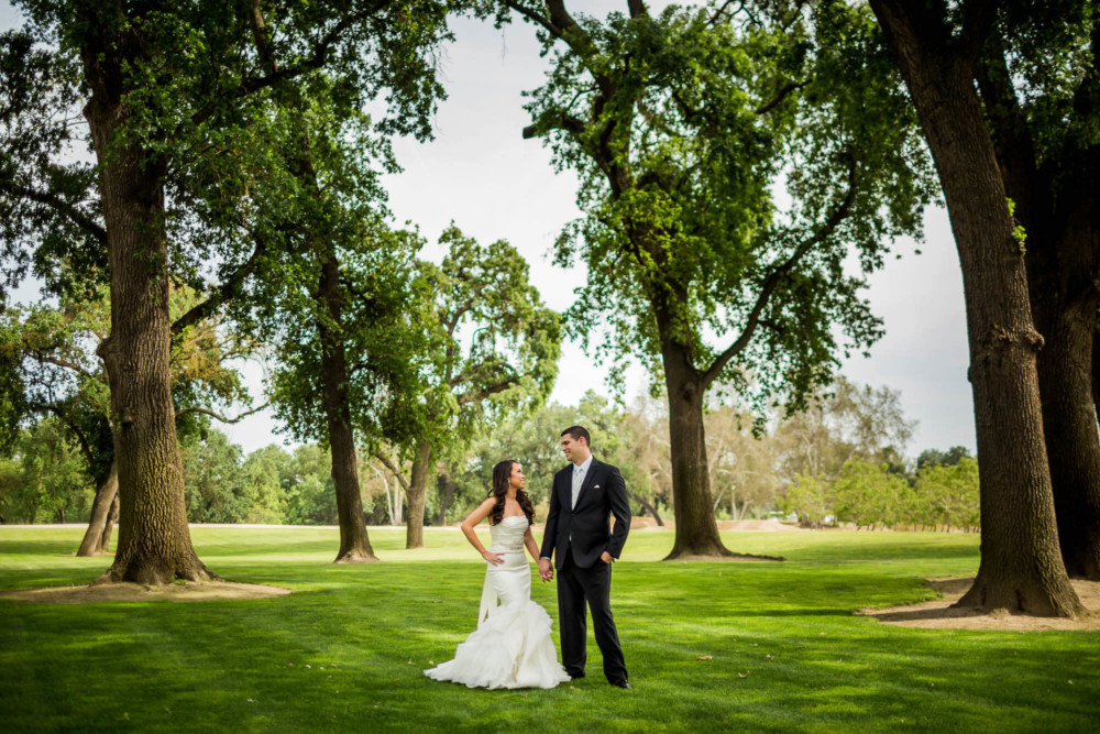 Portrait of bride and groom looking at each other among large trees