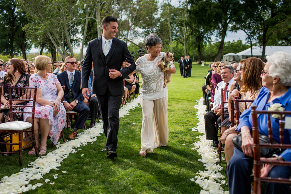 Bride's mother carries a dog down the aisle