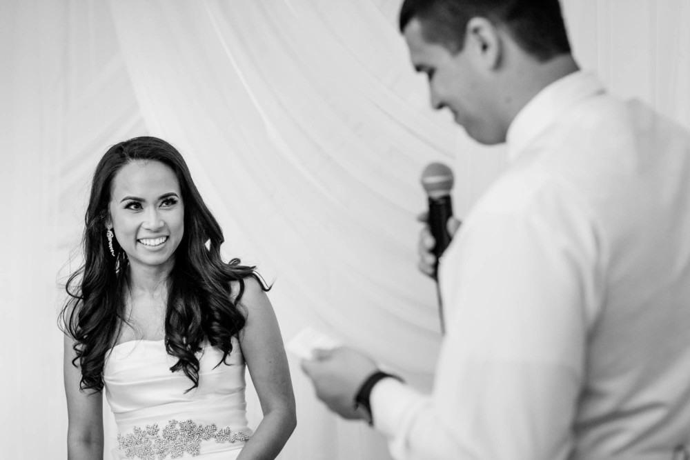 Bride smiles at the groom during his wedding speech