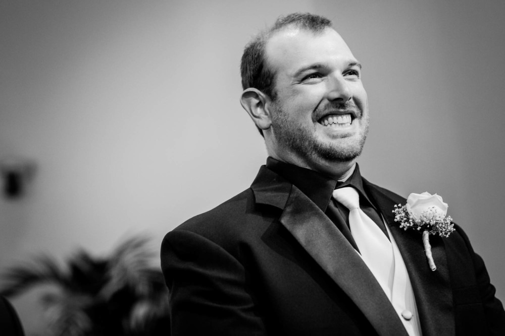 Groom smiles upon seeing his bride enter the church