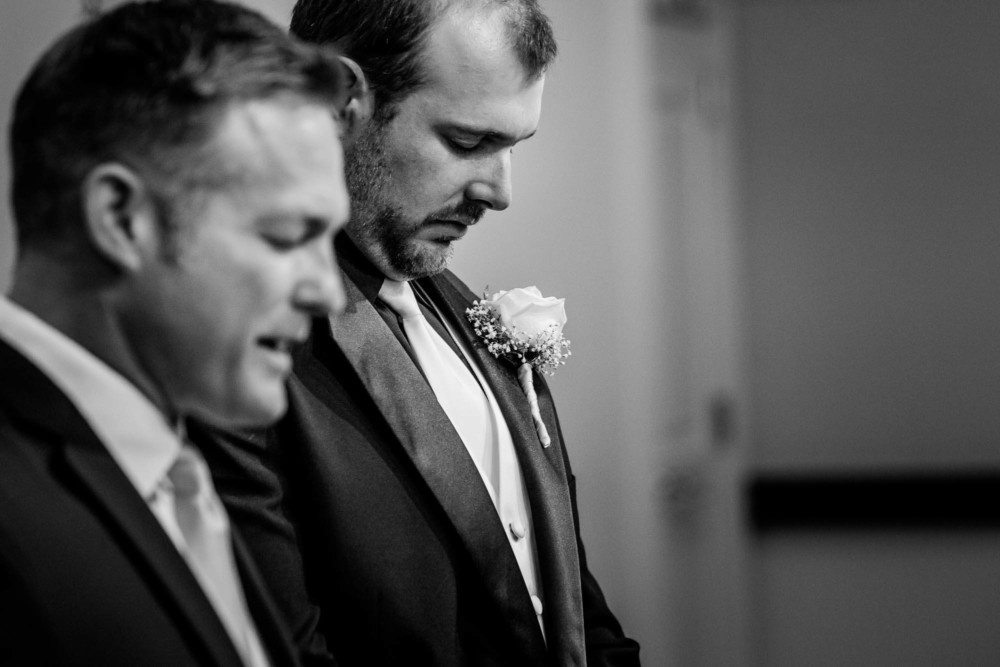 Groom and pastor pray at the start of a wedding ceremony