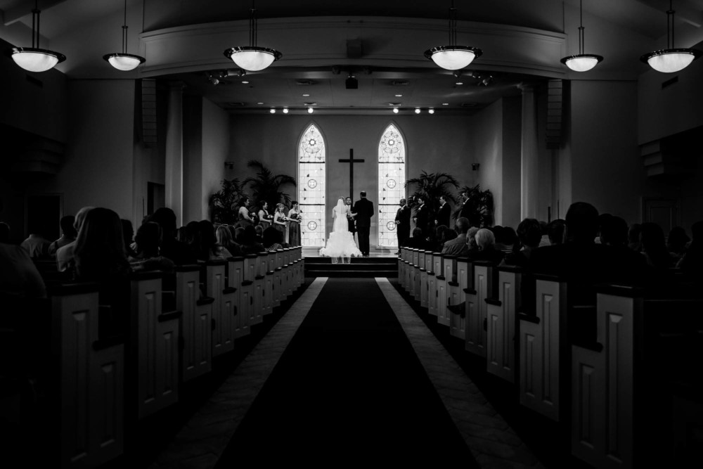 wide view of church with bride and groom at the altar in black and white