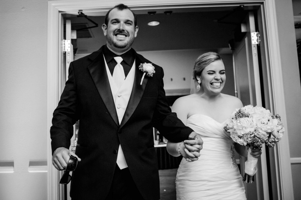 Bride and groom enter their reception smiling