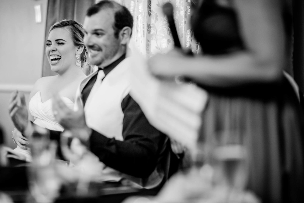 Bride and groom react with laughter during wedding toasts