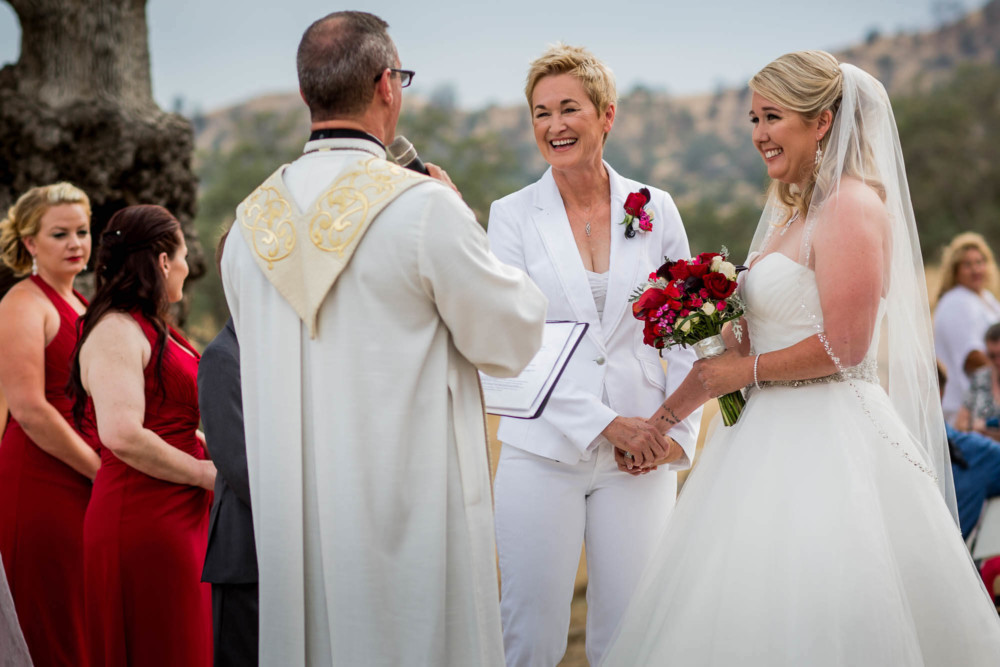Both brides laugh in reaction to the ministers comments