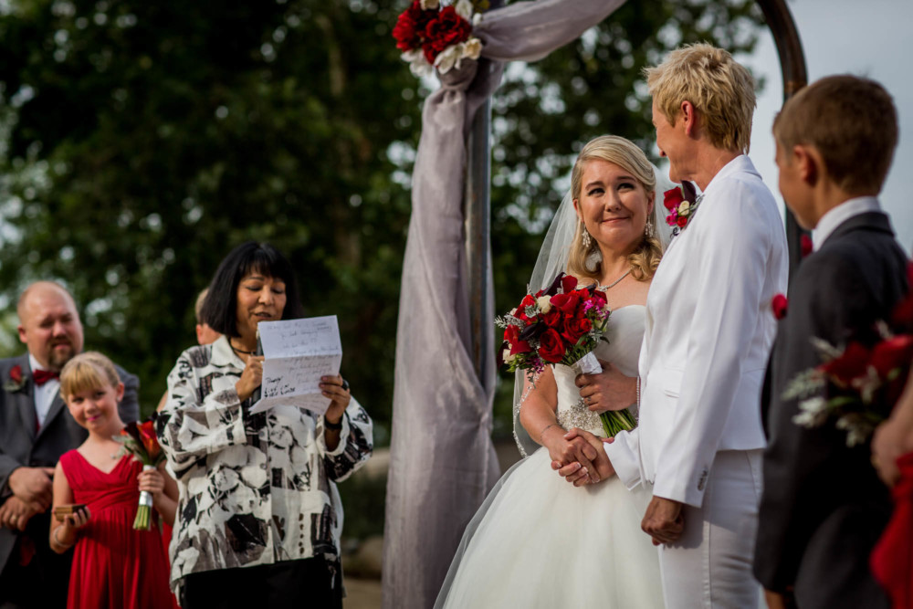 Brides hold hands as a reader reads the text of the Supreme Court Marriage Equality decision
