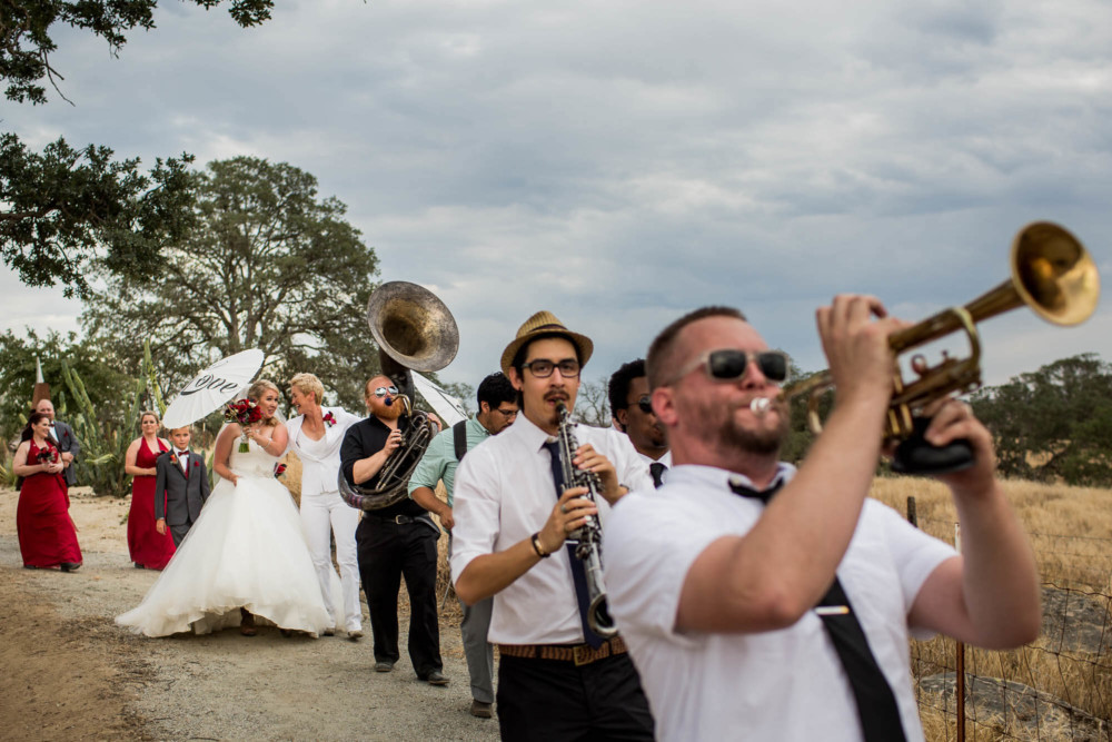 Brides laugh as they follow the band in the second line after the ceremony