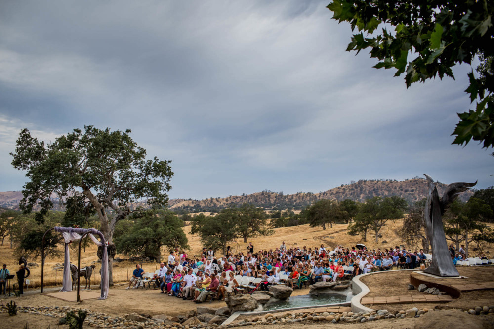 Wide view of the wedding guests, oak trees and rolling foothills and brown grasses