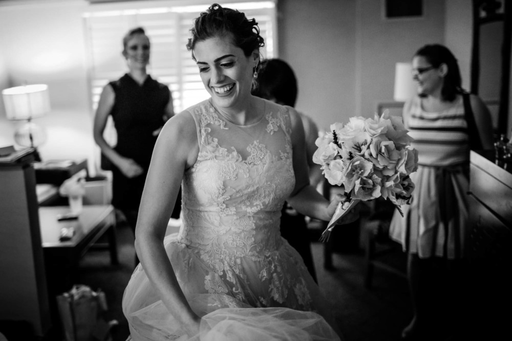 Bride smiles as she leaves the hotel room in her dress