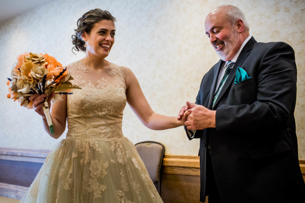 Father of the bride holds her hand in an emotional moment before the ceremony