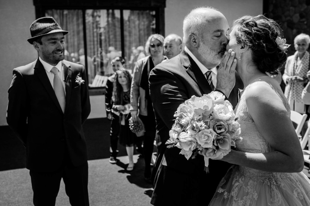 Father of the bride gives her a kiss before handing her off to her groom