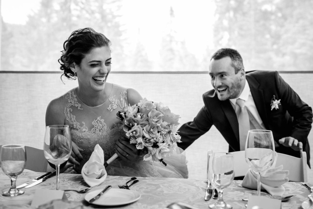 Bride laughs as groom struggles to help her with her chair