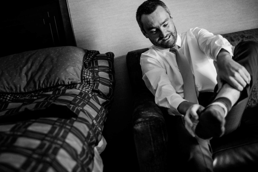 Groom strains as he puts on his shoes before the wedding