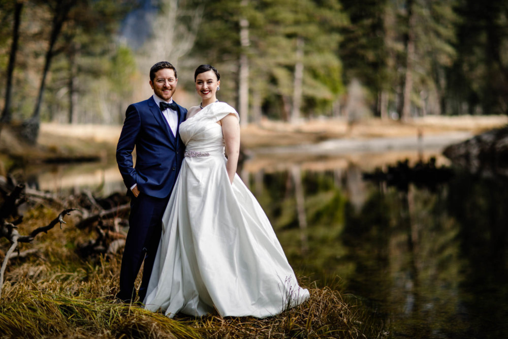 Portrait of a bride and groom standing on an island in the Merced River