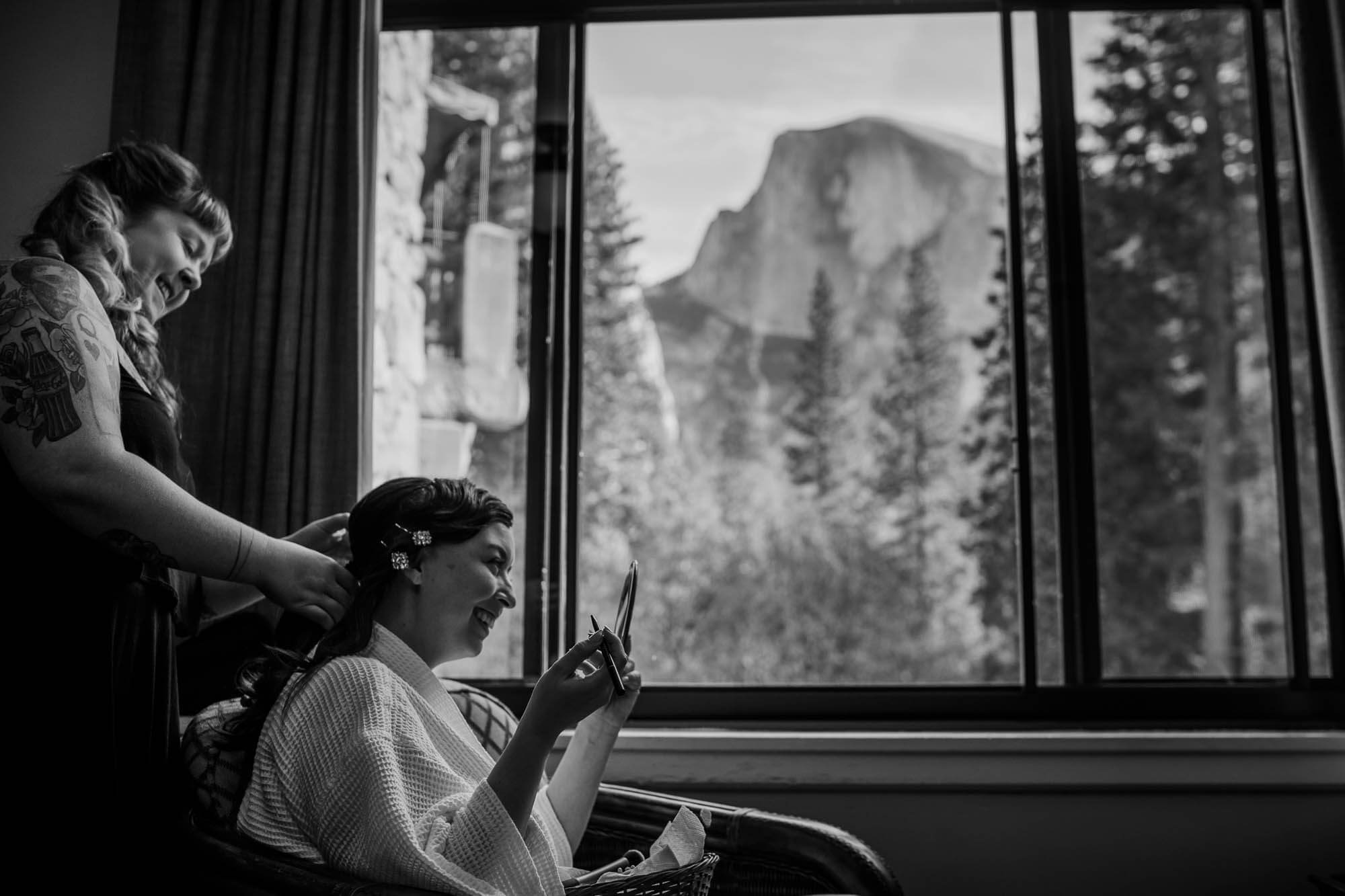 Bride her hair done in front of her room window with a view of Half Dome