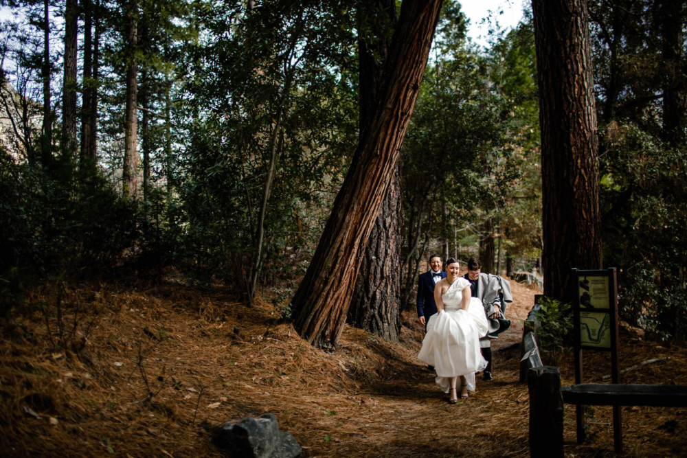 Bride, groom and attendant walk through the forest