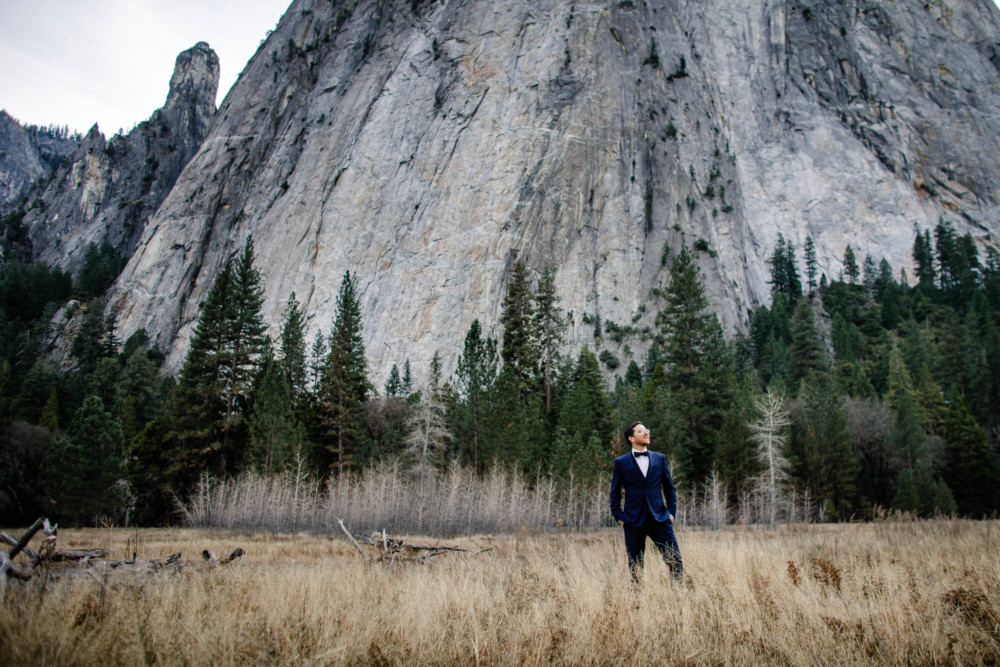 Portrait of a groom standing in a meadow in front of a granite cliff in Yosemite