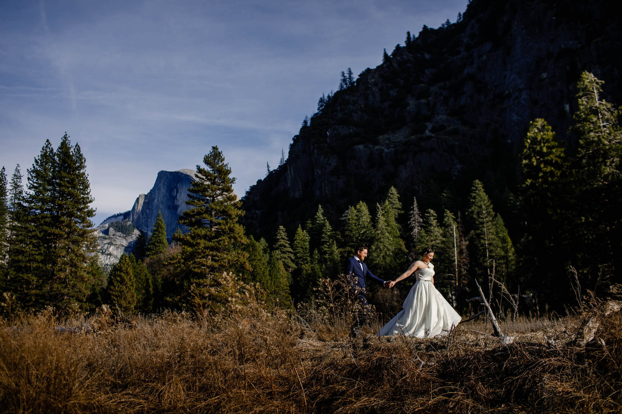 Bride leads the groom as they walk in front of Half Dome in Yosemite