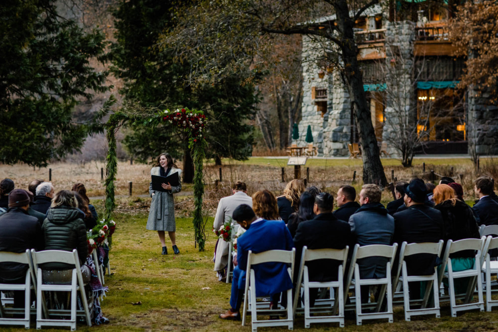 Officiant and wedding guests wait for the ceremony to start in front of the Ahwahnee hotel and Yosemite Falls