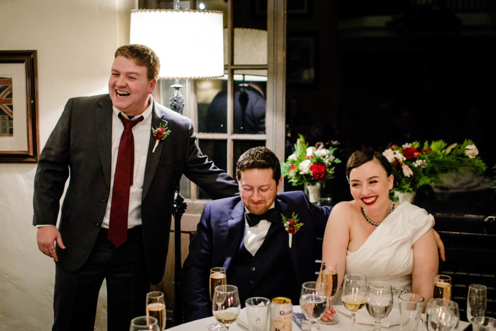 Best man, groom and bride laugh during the toasts
