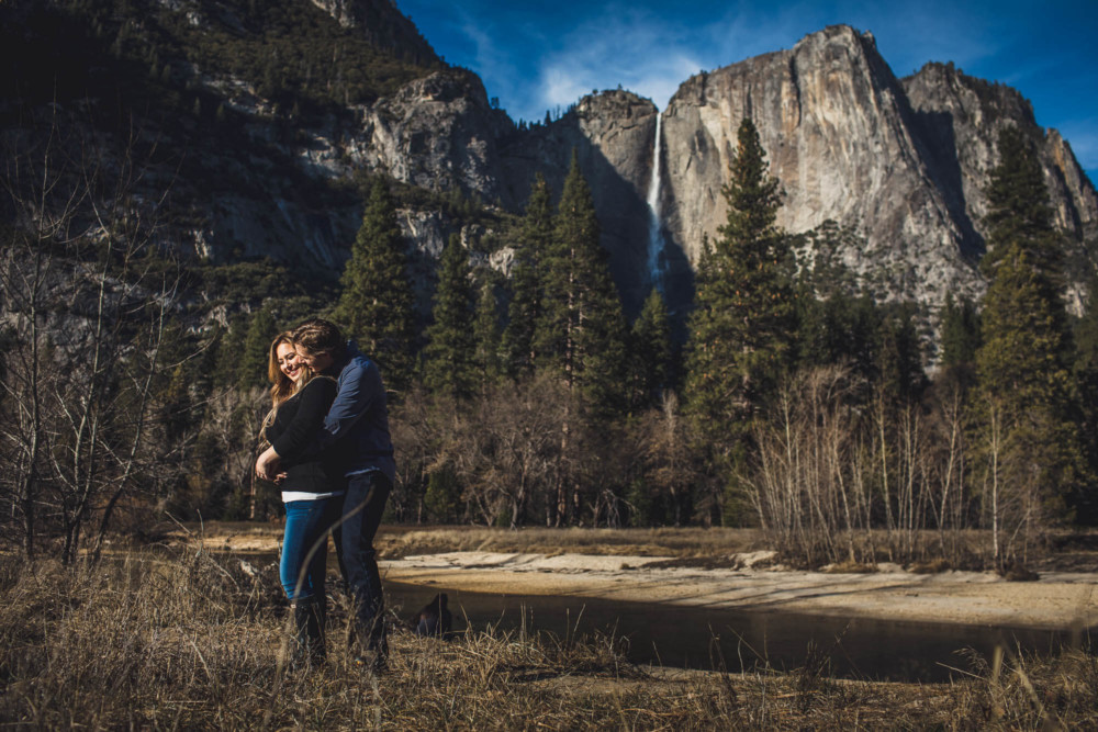 A couple hugs in front of Yosemite Falls in winter