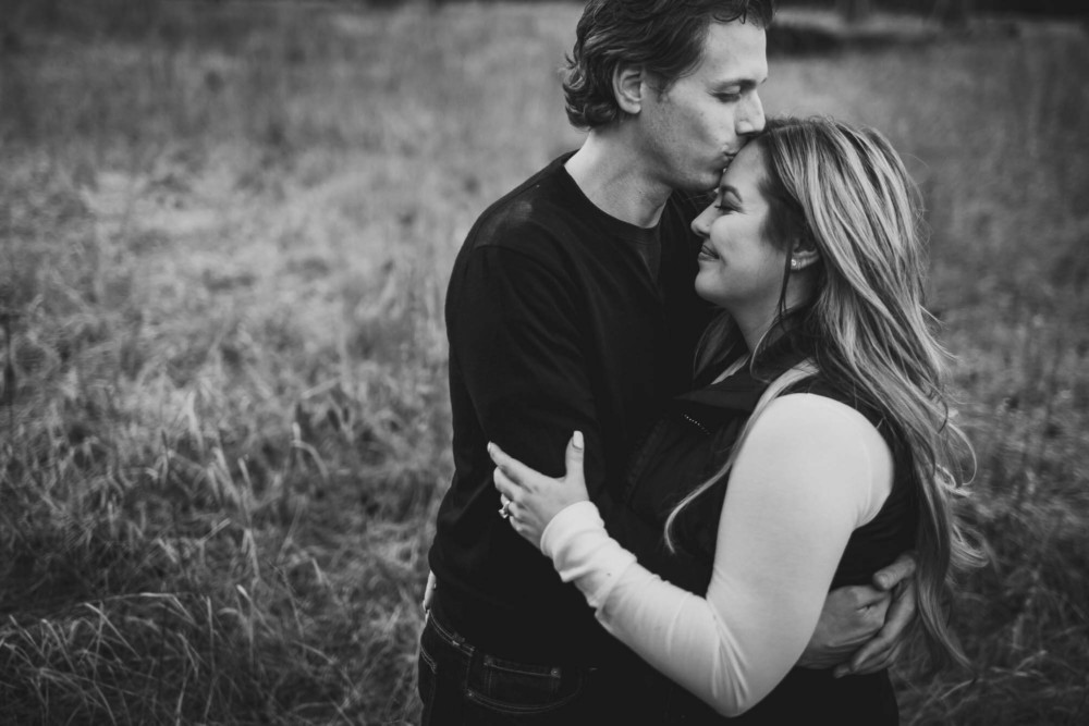 Man kisses his girlfriends forehead during their engagement session