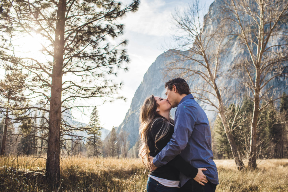 Man and woman kiss in a meadow in Yosemite Valley