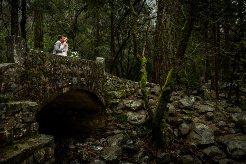 Groom kissing bride on a bridge over Bridalveil creek