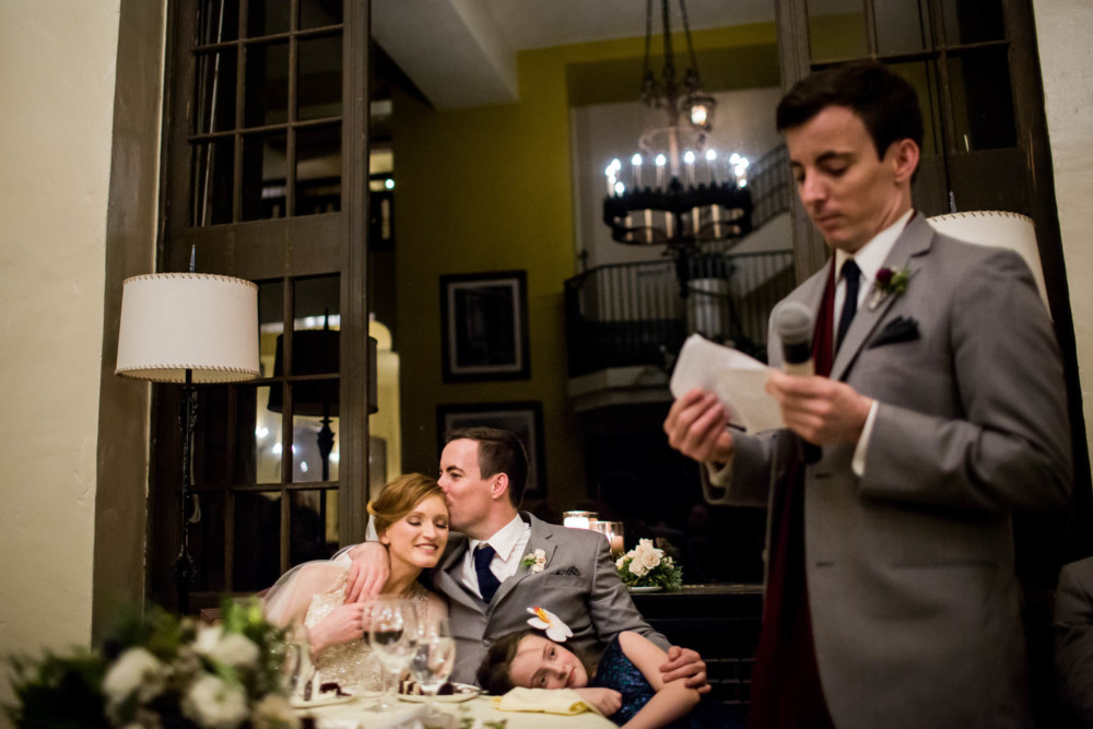 Groom kissing the bride on the forehead during the best man's speech in the solarium at the Majestic Yosemite Hotel
