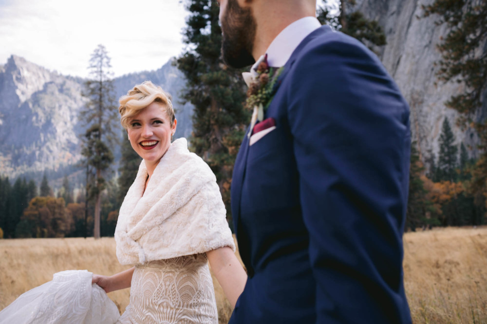 Bride looks at her groom while walking through Yosemite Valley