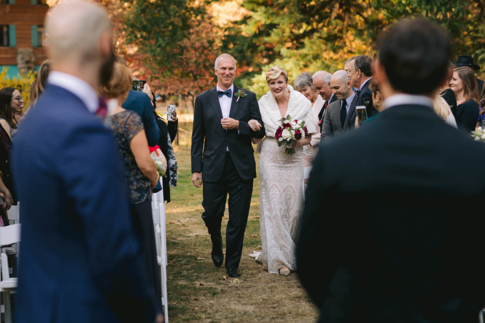 Bride makes eye contact and smiles at groom while walking down the aisle during their Yosemite Wedding
