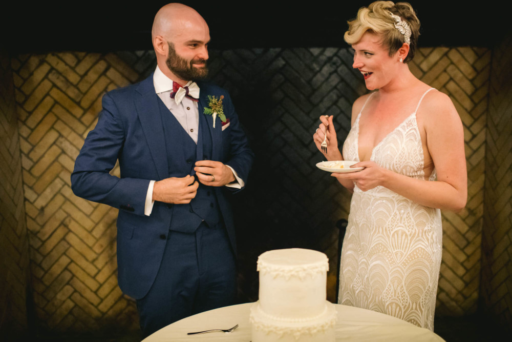 Bride with a mischievous expression before feeding groom a piece of cake