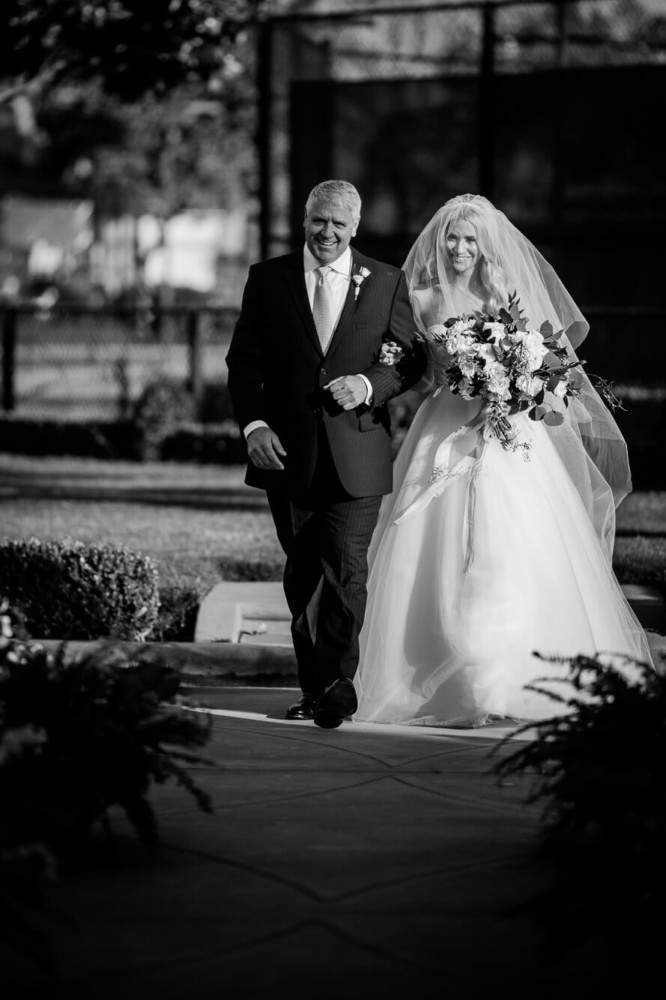 Father of the bride walks his daughter down the aisle at her wedding ceremony