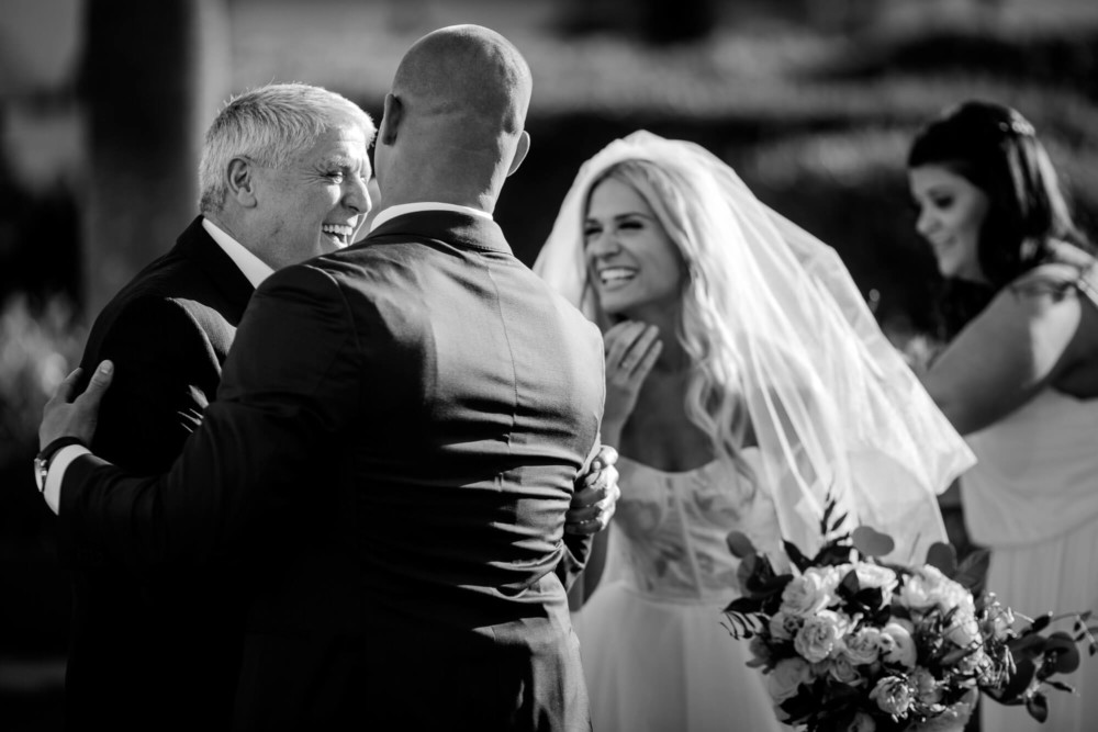 Bride and her dad share a laugh with the groom during the wedding ceremony